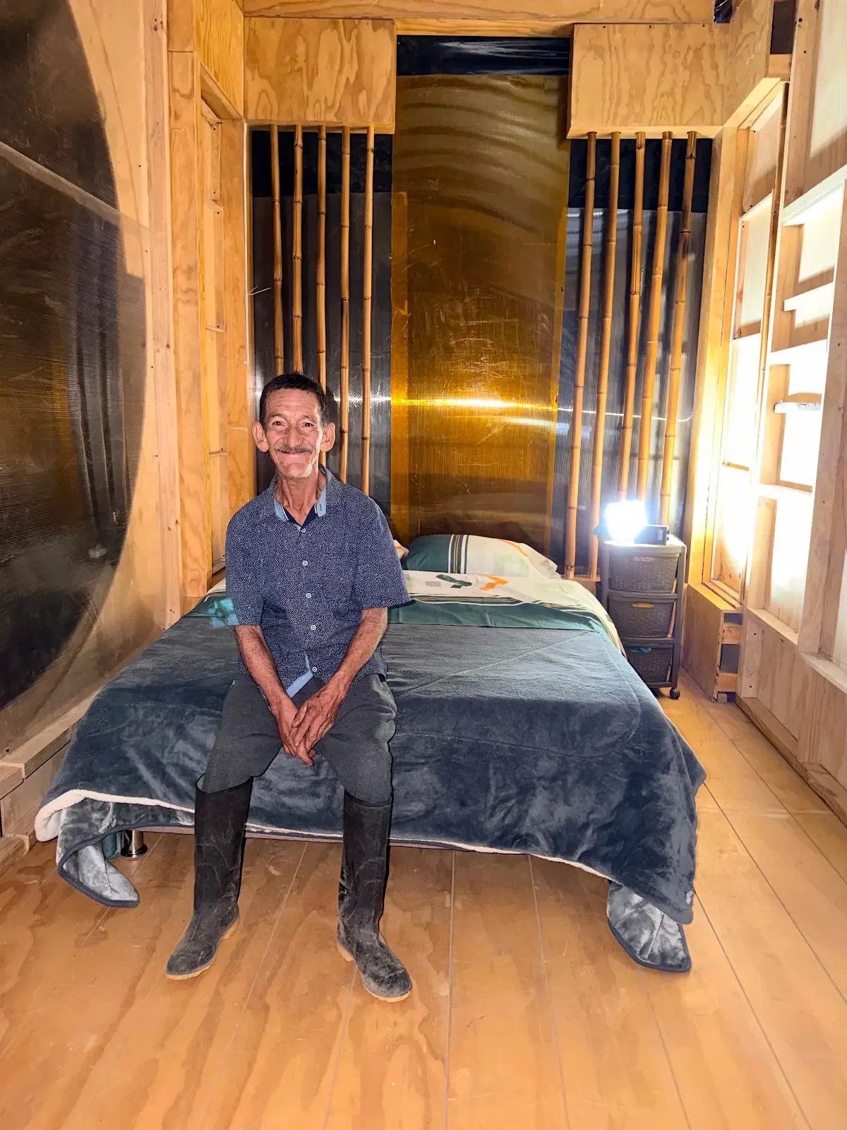 Un hombre sentado dentro de un espacio de vivienda con paredes de madera.